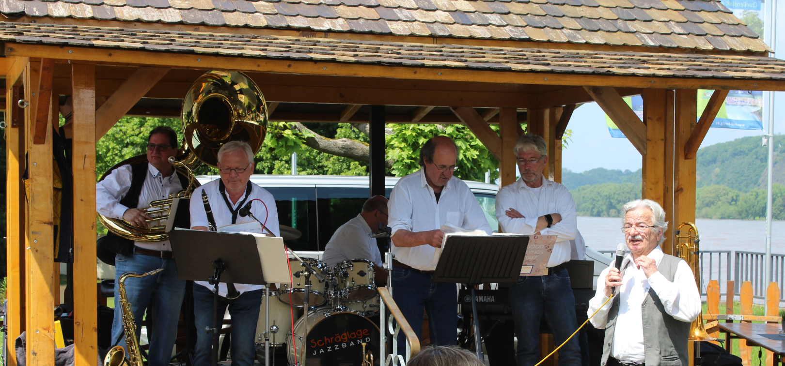 “Der Vorsitzende von FORUM Kultur, Bernd Lang, begrüßte auch im Namen des Vorsitzenden von BREISIG.live, Rüdiger Kowalsky, am Pfingstmontag die Besucher von “Jazz im Park“ und die Band “Schräglage“ auf der Bühne.“ Credit: Kulturverein BREISIG.live (Michael Lüdtke)